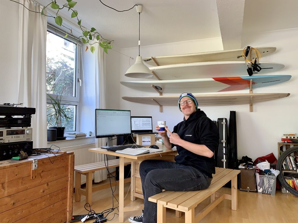 Das Auge arbeitet mit: Bei Henning Rüpke geht es um die Details. Surfbretter an der Wand, wpd windmanager Becher in der Hand. Dafür gibt es von uns 5 Home-Office-Sterne.